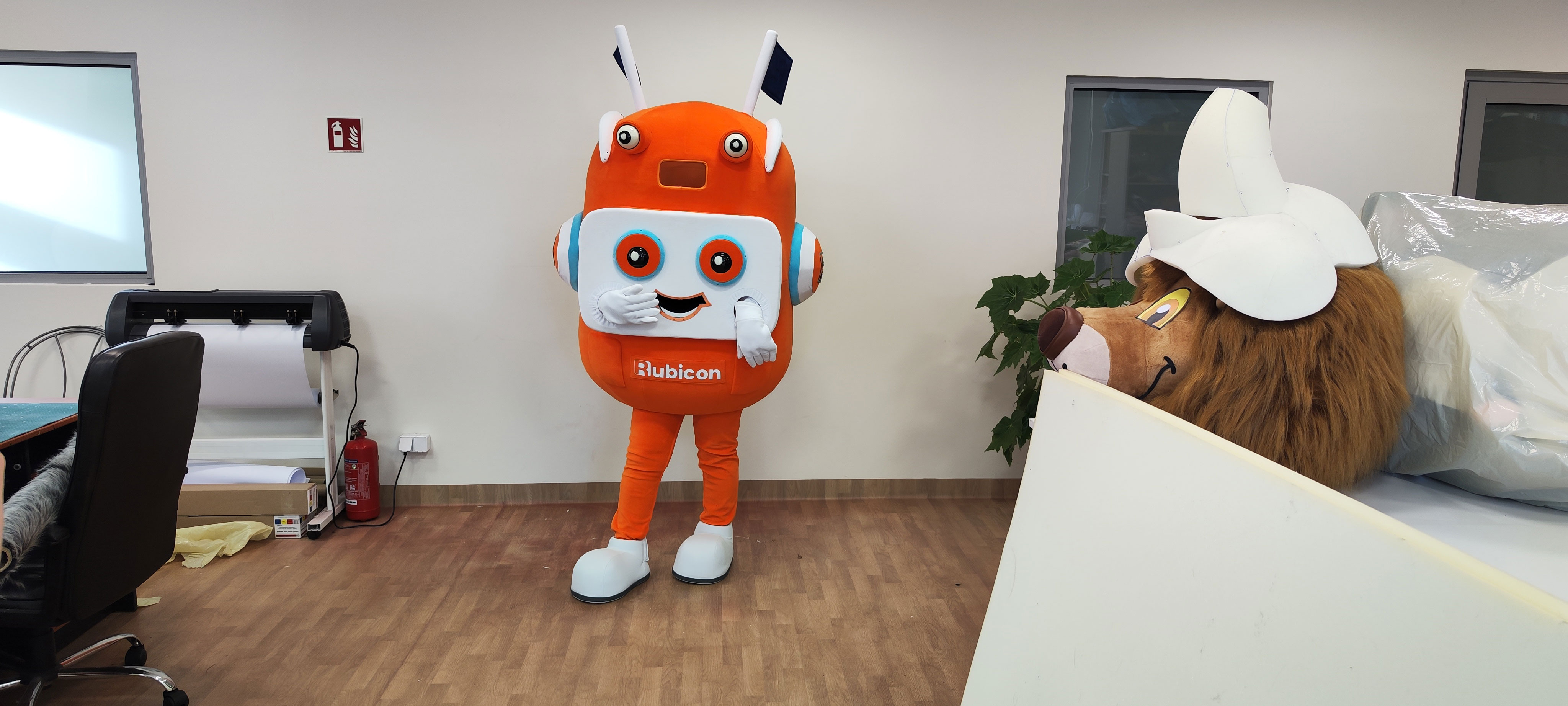 Na fotografii widnieje strój reklamowy stylizowany na postać robota pozujący do zdjęcia w siedzibie firmy Elabika